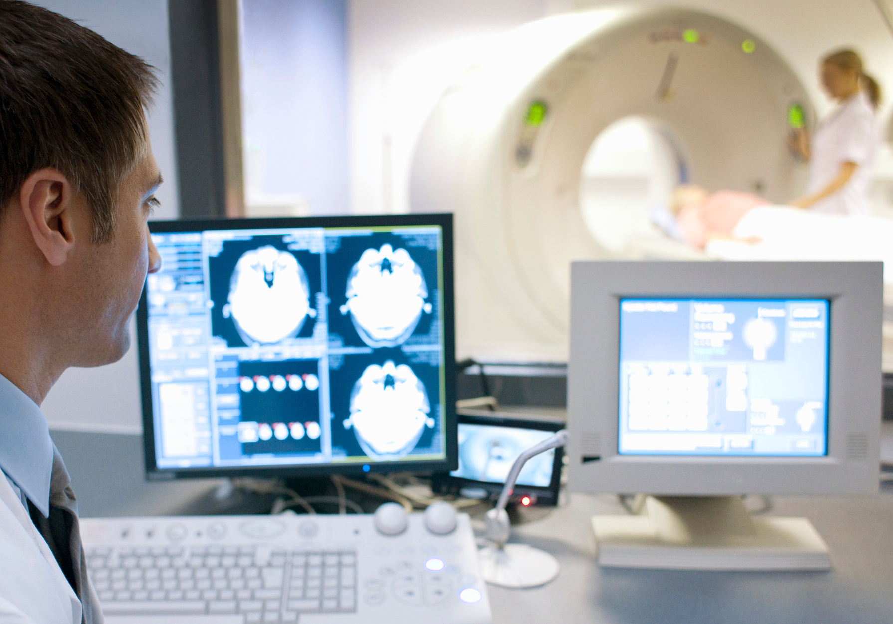 CT scanning. Radiographers taking a computed tomography (CT) scan of a patient.